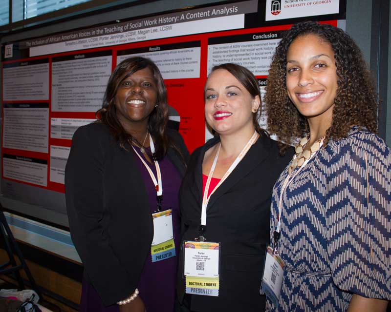 Three doctoral students standing in front of research posters.