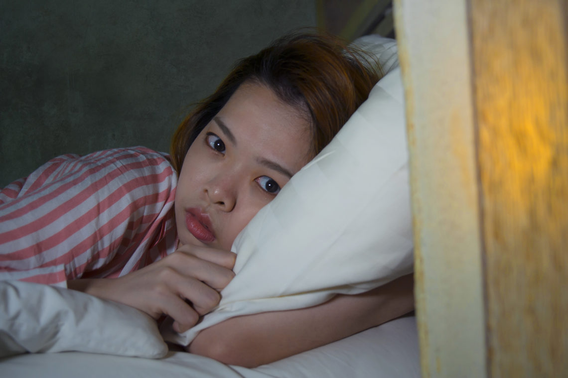 young beautiful sad and depressed Asian Korean girl lying on bed late night awake looking thoughtful suffering insomnia sleeping disorder feeling tired and worried in woman depression concept