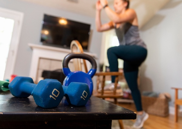 Athens resident Amy Tucker uses a chair to do step-ups as she follows along in a Zoom meeting workout with her local gym in her Watkinsville home. (Photo by Andrew Davis Tucker/UGA)